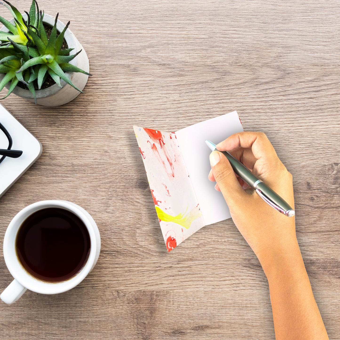 Schreibszene mit Solren Notizbuch, einer Tasse Kaffee und grüner Pflanze, aufgenommen von oben.