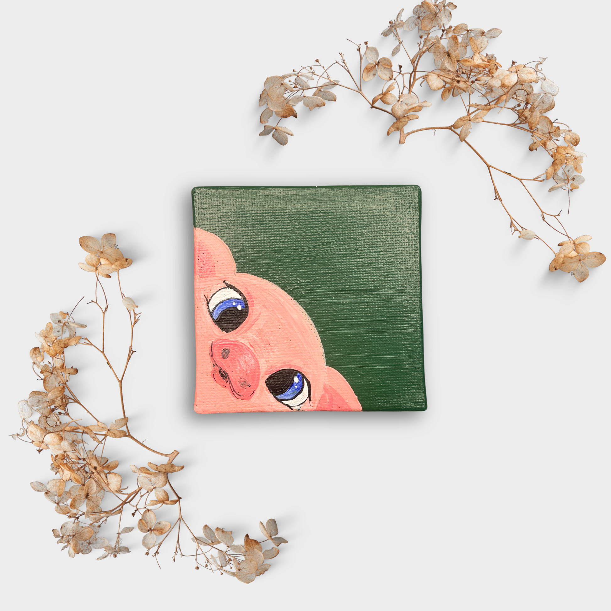 Handgemalte Mini-Leinwand (7×7 cm) mit niedlichem Schweinchen-Motiv auf grünem Hintergrund, dekoriert mit getrockneten Blütenzweigen – charmante Kunst für Wand oder Tisch.

