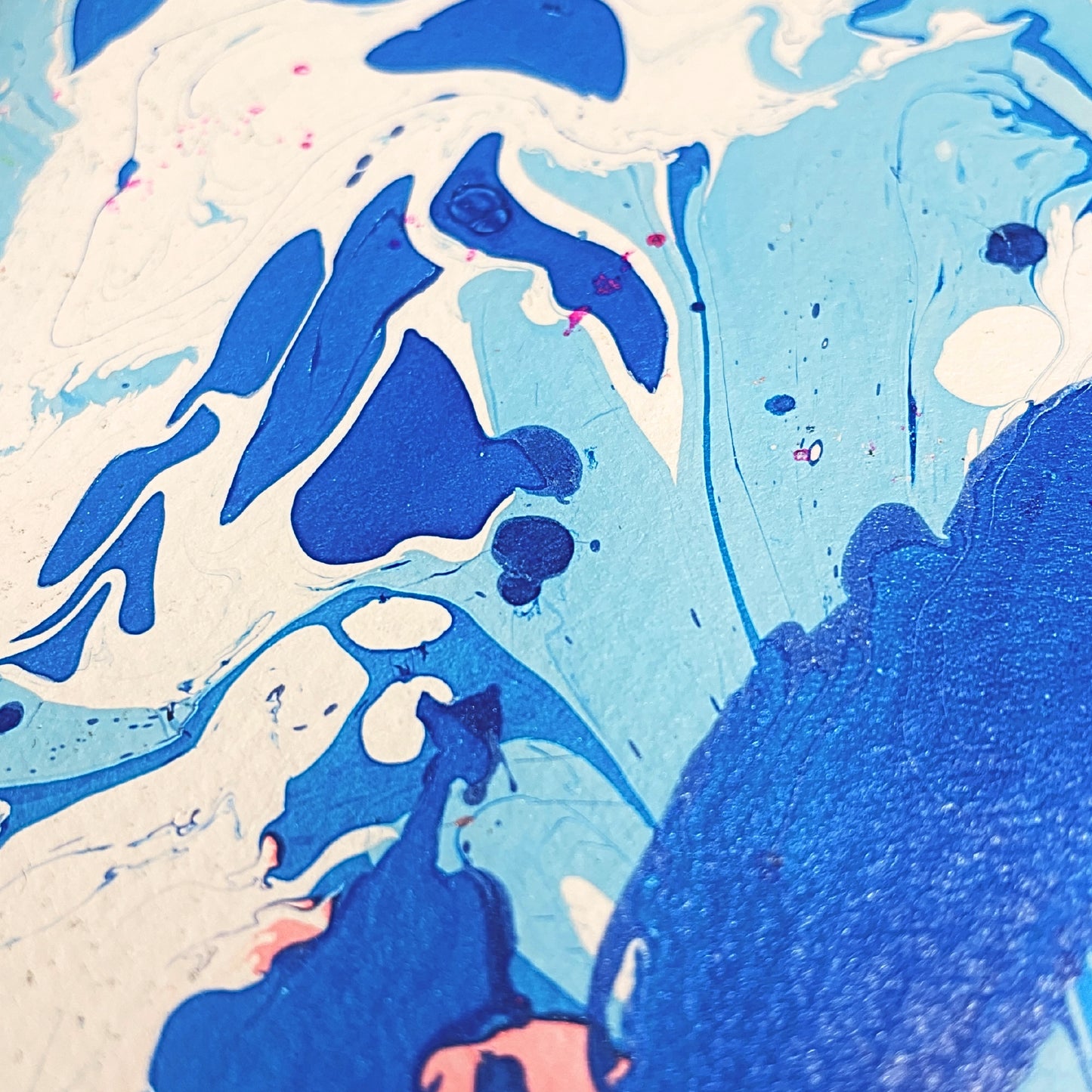 Extreme Nahaufnahme der Marmormusterung des Aven Notizbuchs, mit kräftigen Blau- und Weißtönen sowie feinen rosa Details.

