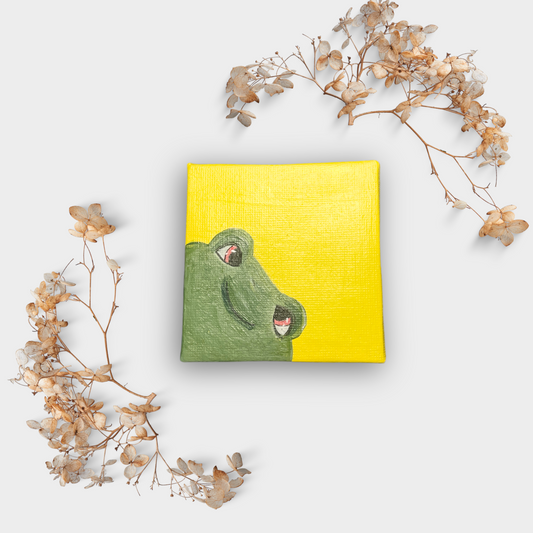 Frontalaufnahme der Mini Leinwand mit grünem Frosch, eingerahmt von zarten Trockenblumen – humorvolles Tiermotiv auf kräftigem Gelb.