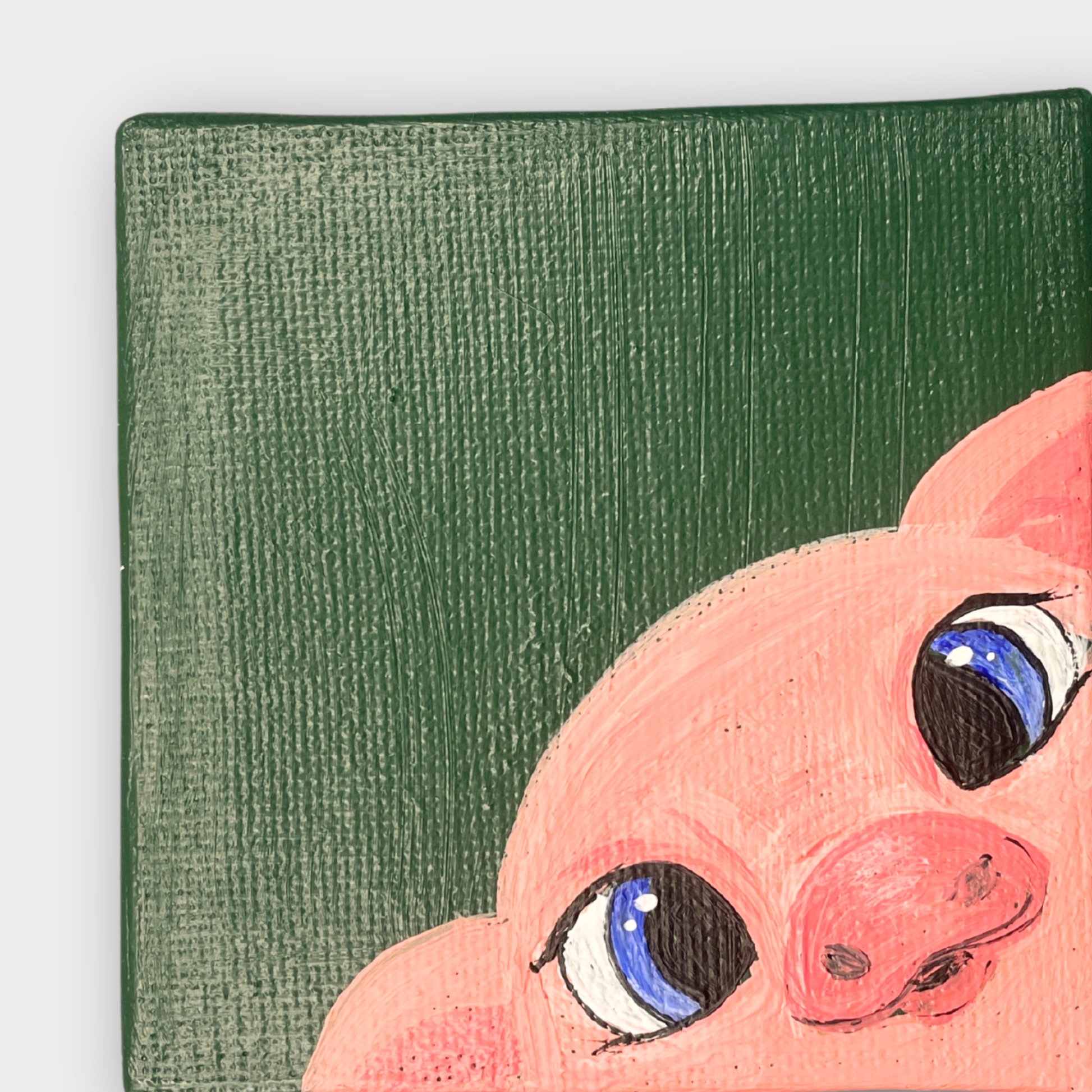 Detailaufnahme einer handgemalten Leinwand mit rosa Schweinchen und großen blauen Augen auf grünem Hintergrund – sichtbare Struktur der Acrylfarbe auf Leinen.