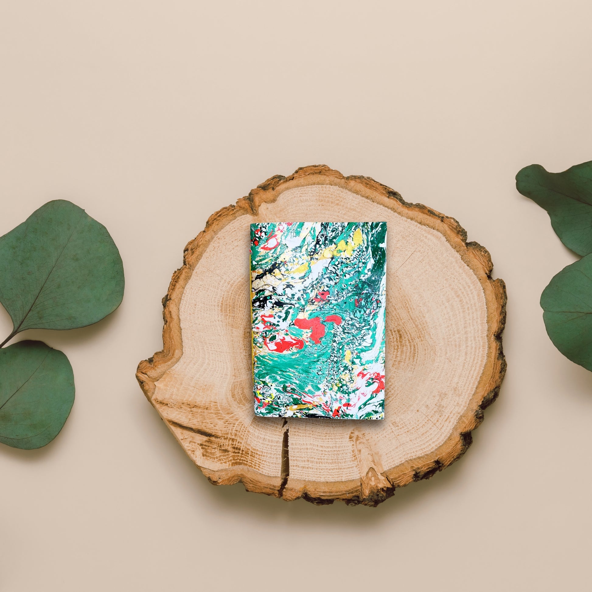 Natürliches Setting: Servin-Notizbuch auf Holzscheibe mit Eukalyptus.